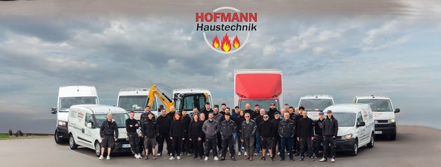 Eine Gruppe von Mitarbeitern steht stolz vor einer Reihe von Firmenfahrzeugen, die für Haustechnik-Dienstleistungen genutzt werden.